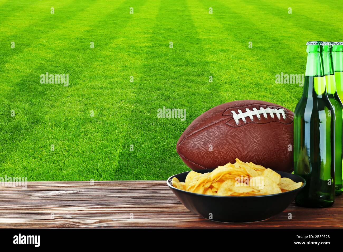 Beer bottles, ball and snack on football field background Stock Photo