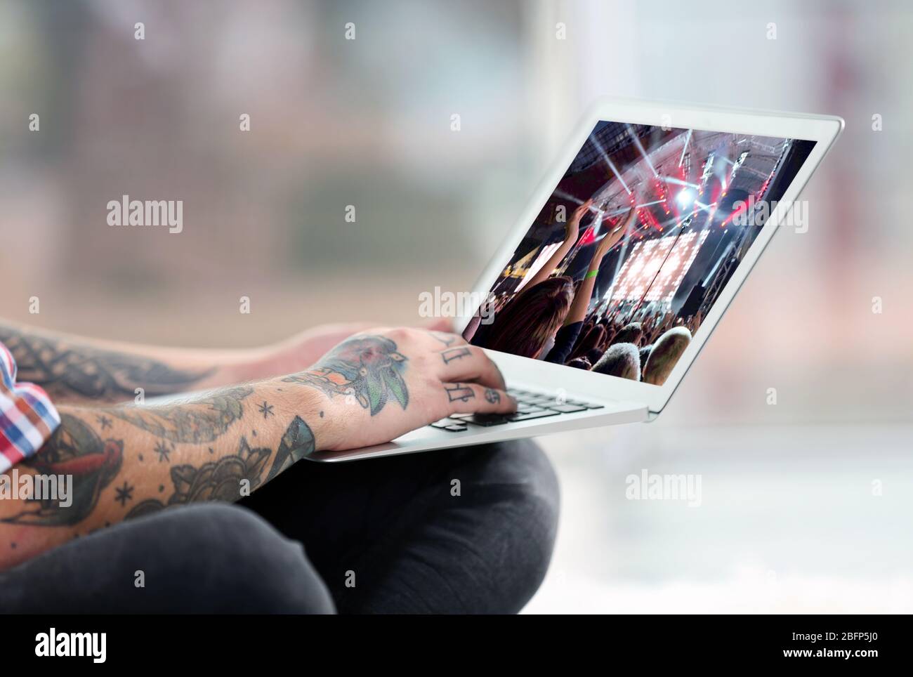 Young man with tattoo using laptop on a floor at home Stock Photo