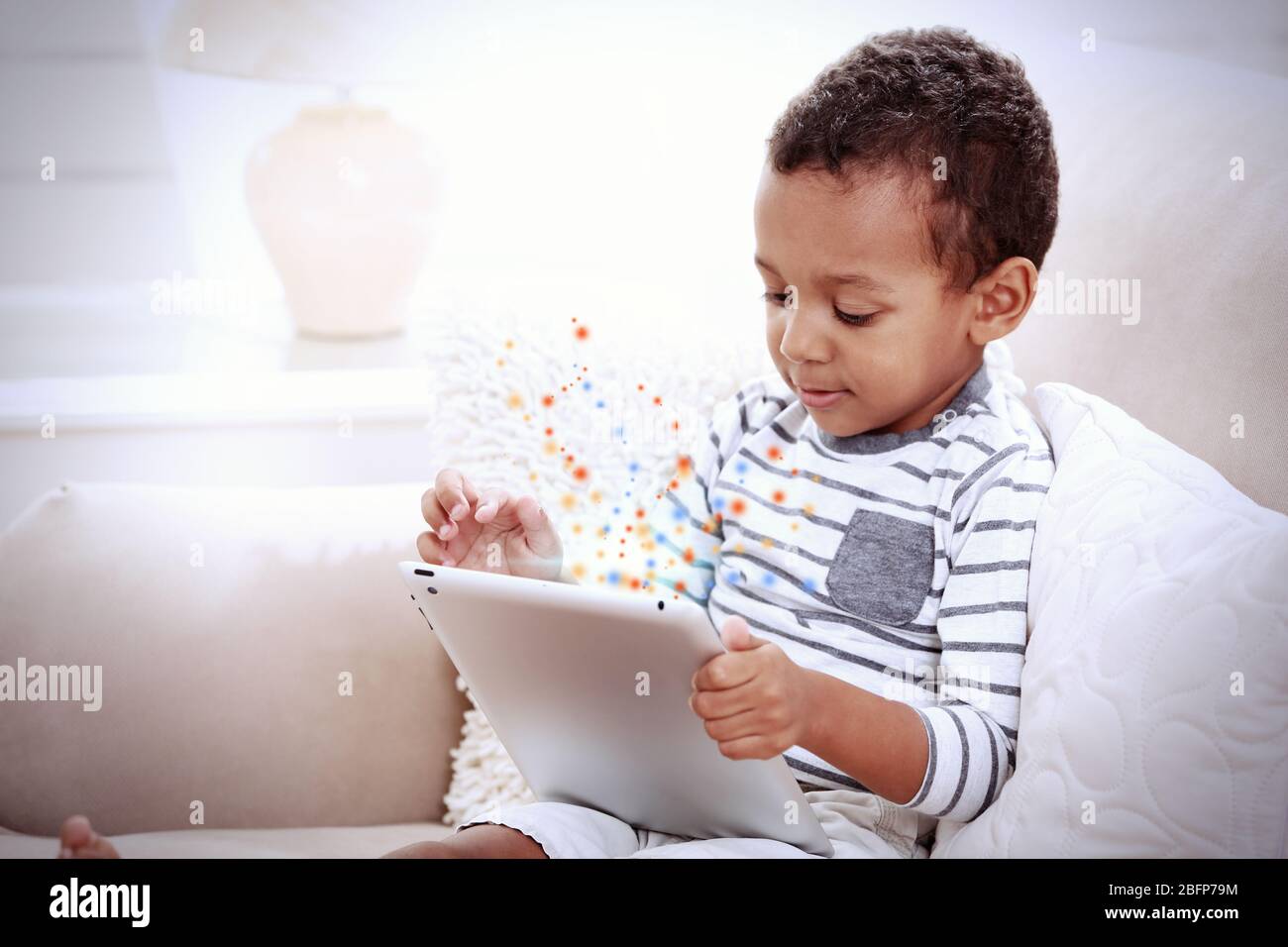Little boy sitting on sofa with tablet in the room Stock Photo - Alamy
