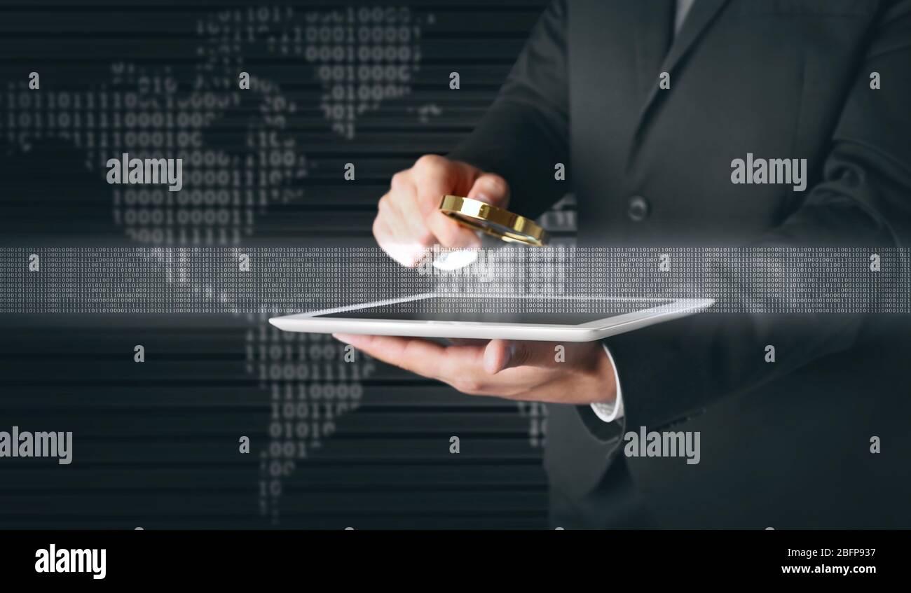 Businessman holding magnifying glass and tablet. Binary code and world map on background. Technology concept. Stock Photo