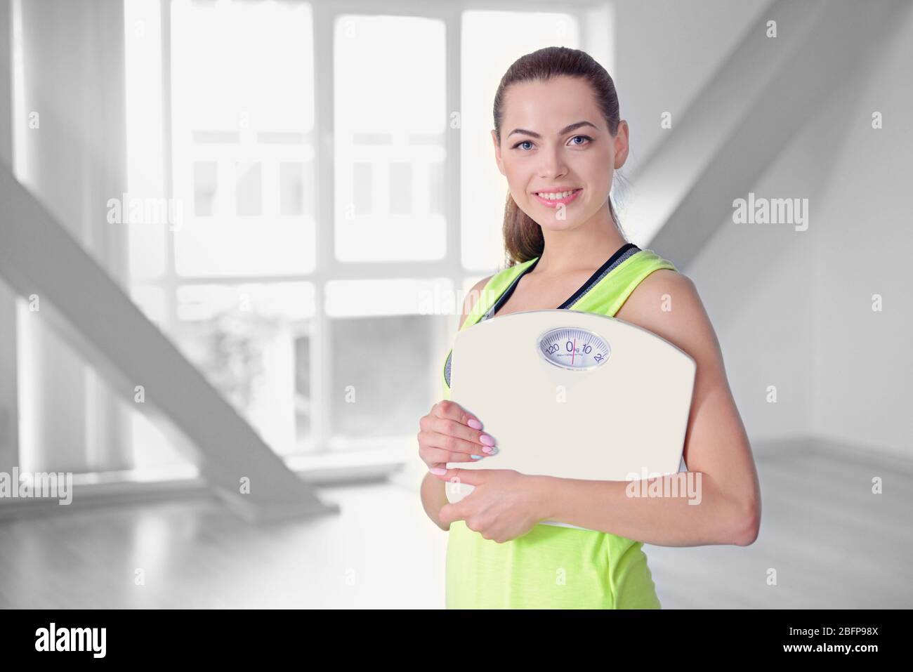 Young beautiful woman with scales on blurred hall background Stock