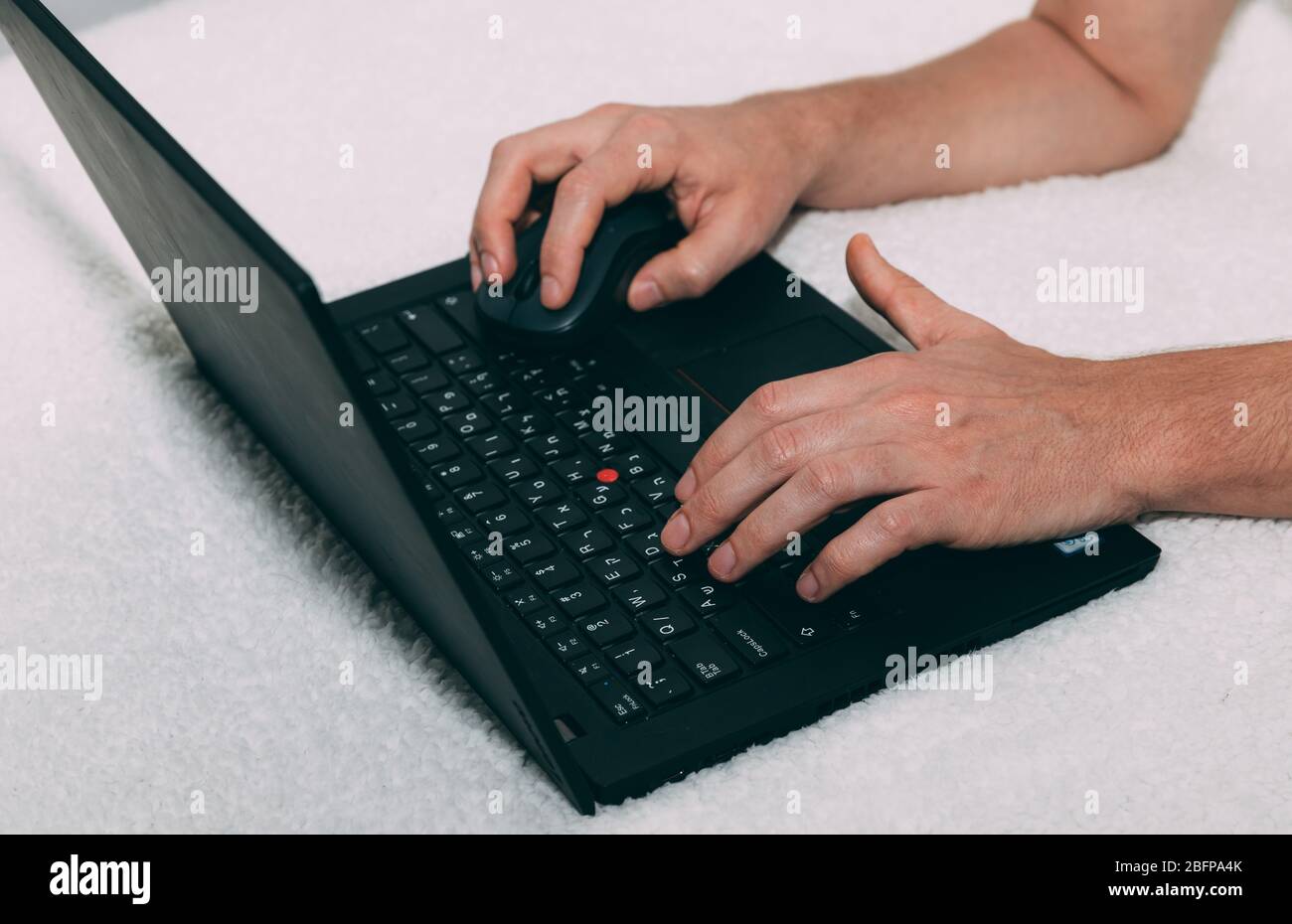 Men's hands are typing on a black laptop with computer mouse. Stay home concept. Order products online. Distance communication. Working from home. Whi Stock Photo