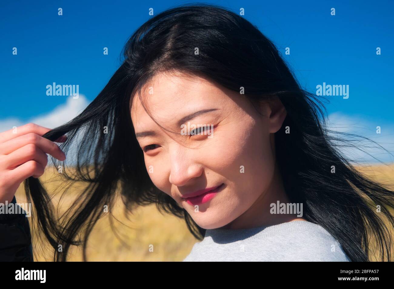 A chinese woman playing with her hair outside within the national seashore scenic area in Cape Cod Massachusetts on a sunny blue sky day. Stock Photo