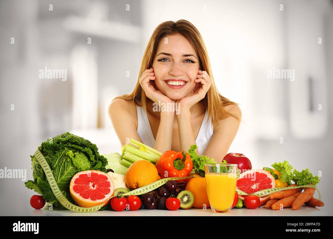 Beautiful young woman with healthy food on blurred kitchen background. Diet concept. Stock Photo