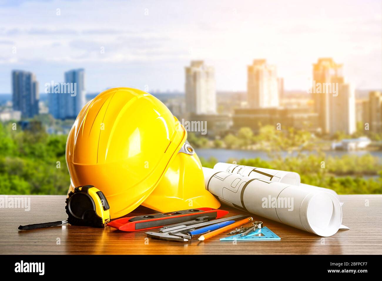 Construction blueprints with tools and helmets on cityscape background Stock Photo