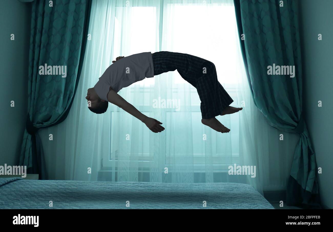 Sleep paralysis concept. Young man levitating over bed Stock Photo