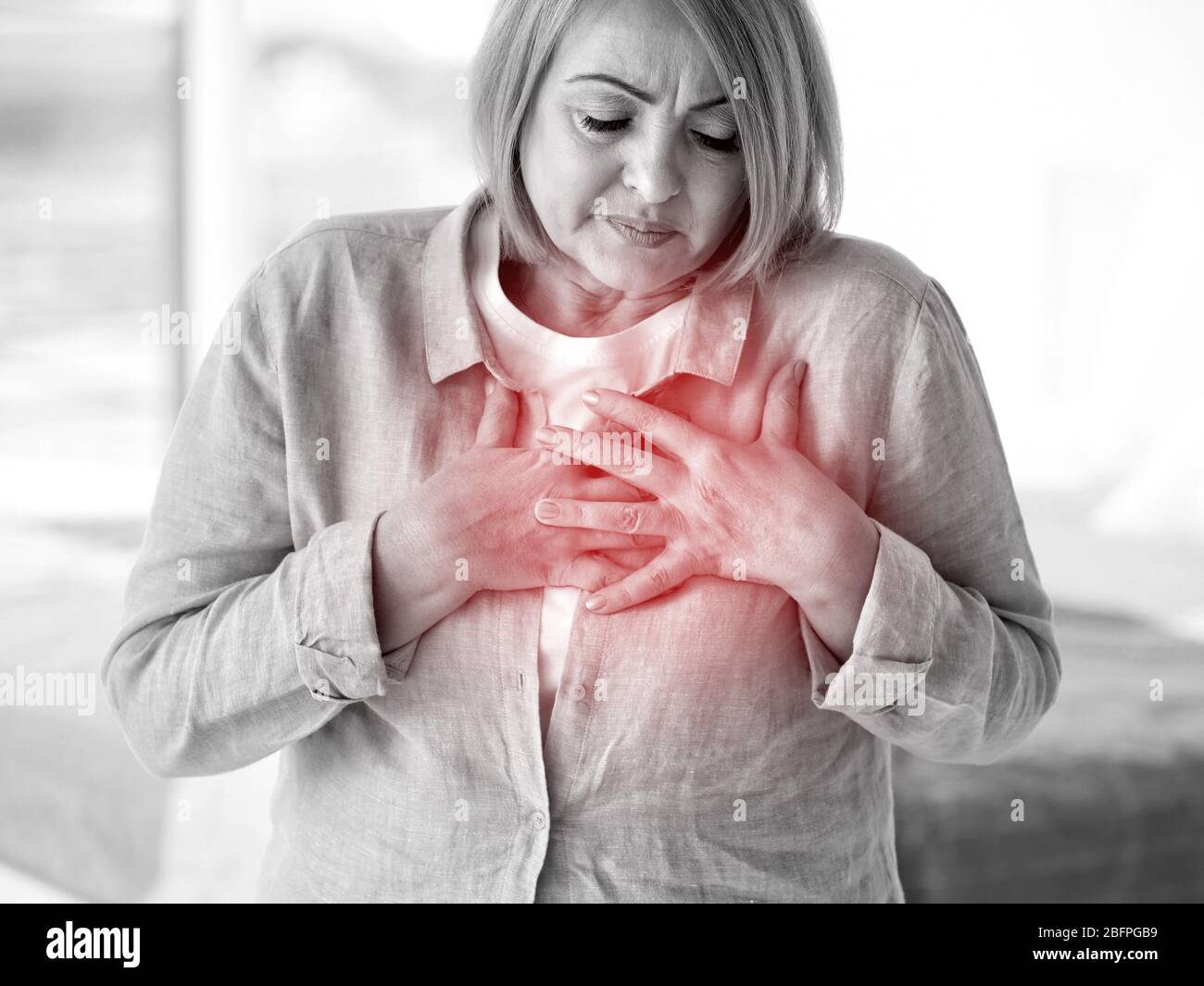 Heart attack concept. Senior woman suffering from chest pain indoor
