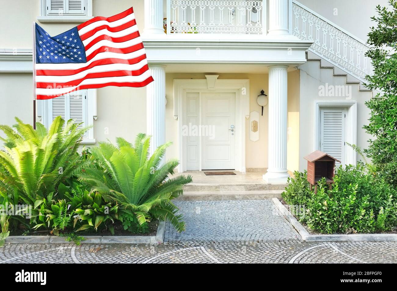 Waving USA flag in front of house Stock Photo - Alamy