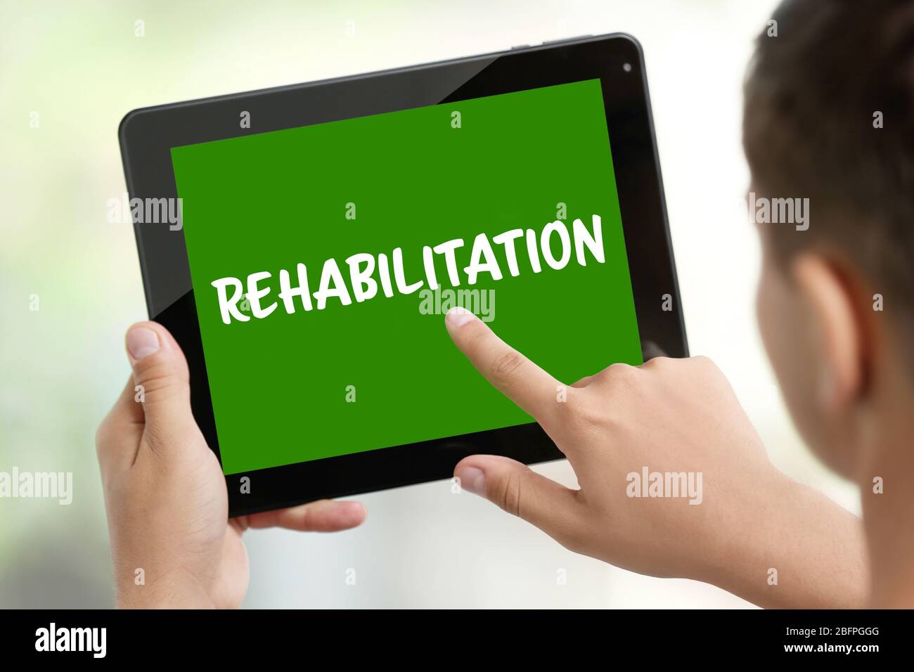 Recovery concept. Man using tablet, closeup. Word REHABILITATION on ...