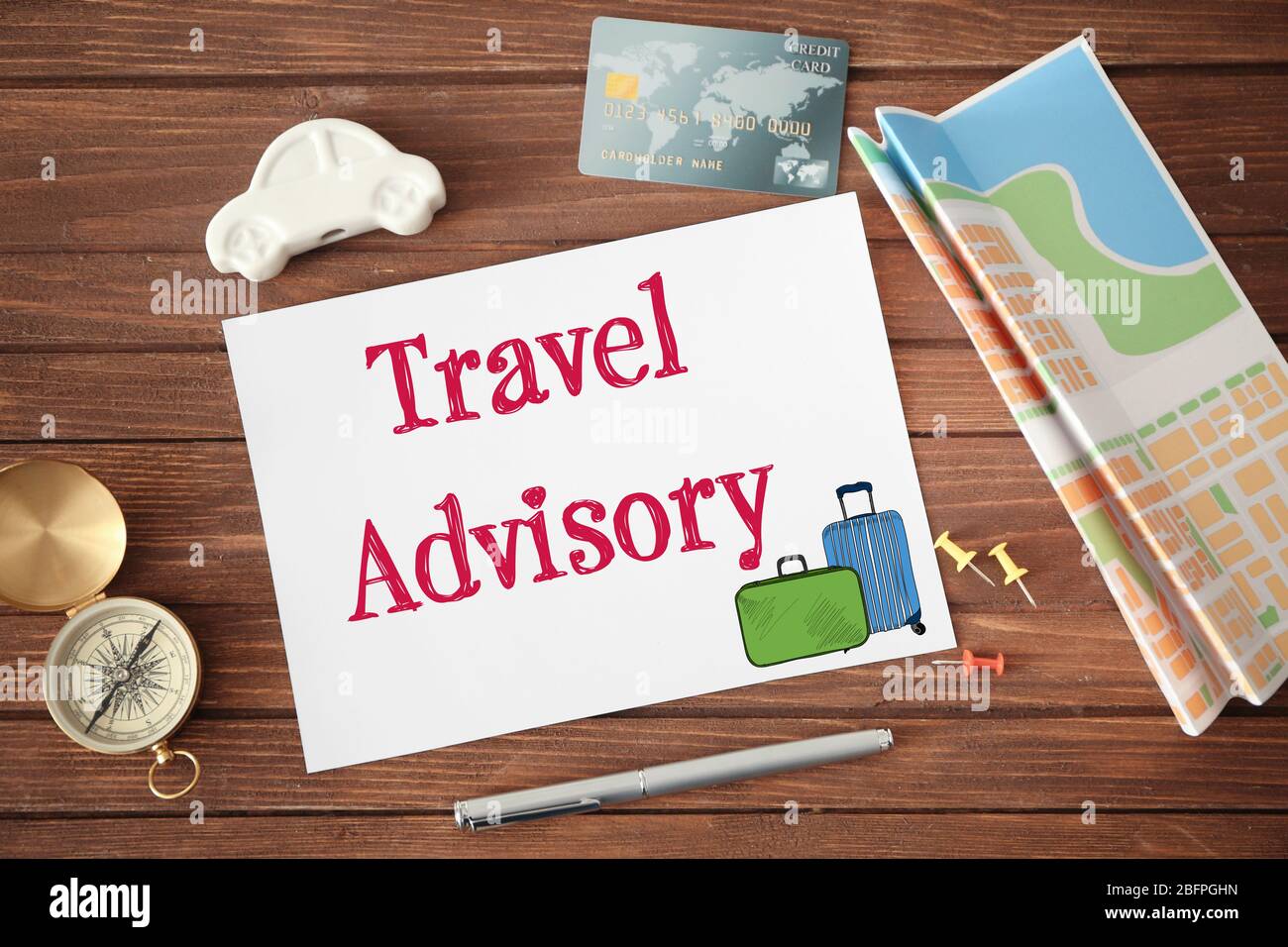 Concept of tourism. Paper with text TRAVEL ADVISORY and credit card on wooden background Stock Photo