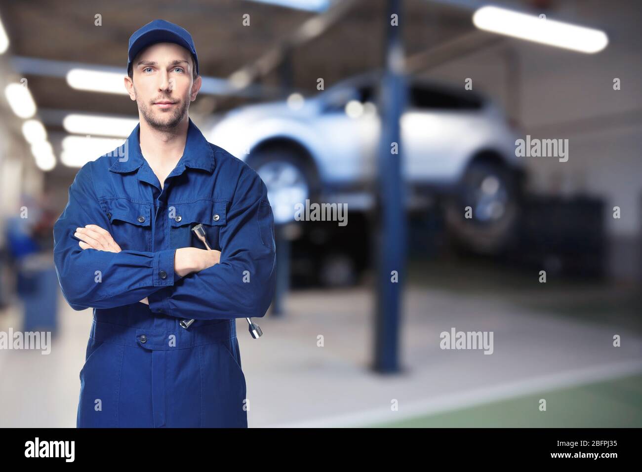 Auto mechanic with tool and workshop on background. Car service concept Stock Photo