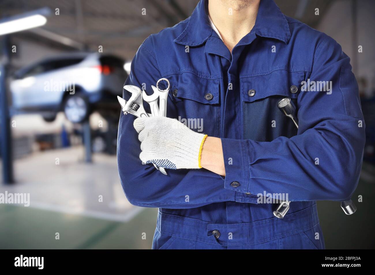Auto mechanic with tools and workshop on background. Car service concept Stock Photo