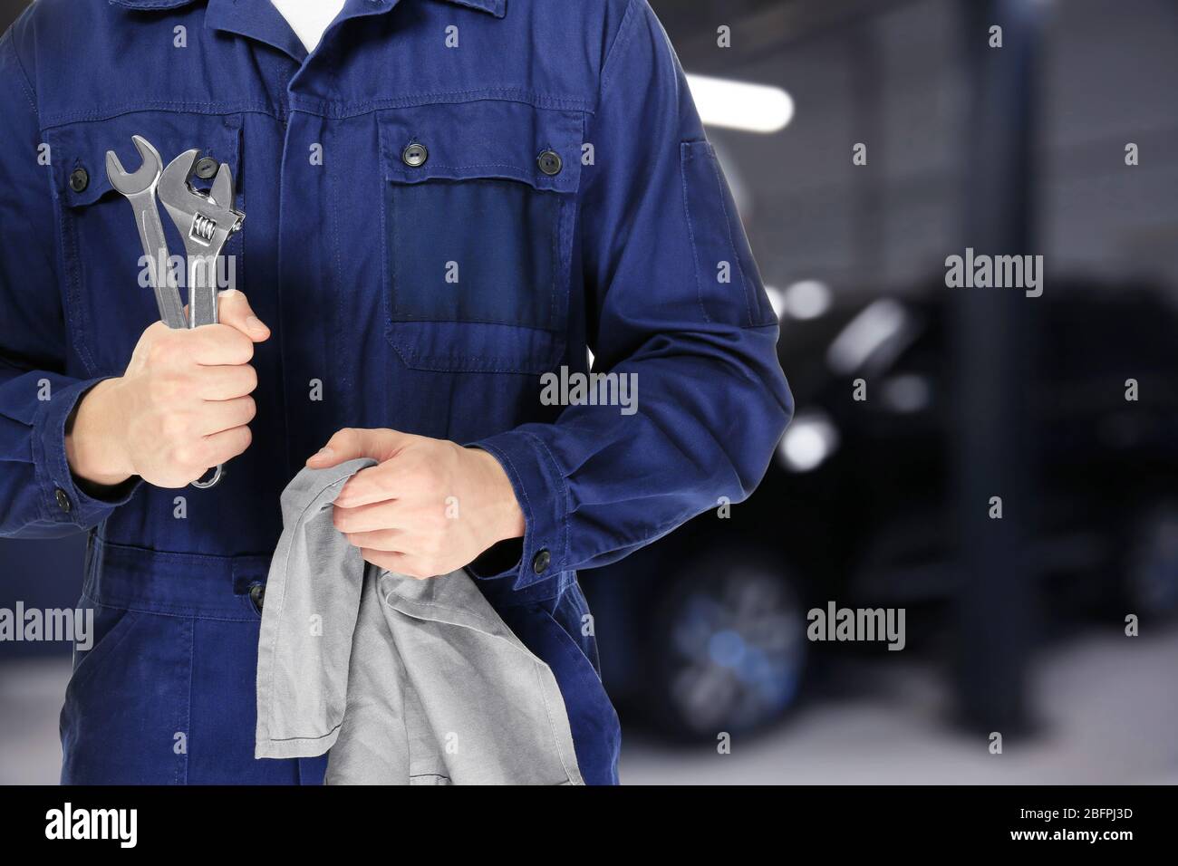Auto mechanic holding rag with tools and workshop on background. Car service concept Stock Photo