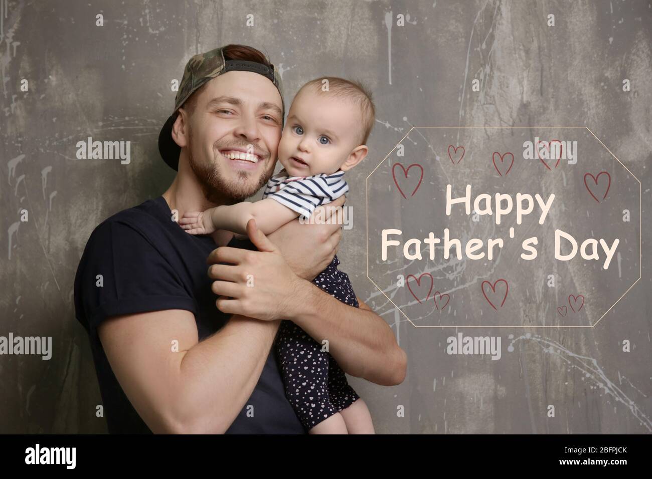 Daddy with cute baby daughter and text HAPPY FATHER'S DAY on grunge background Stock Photo