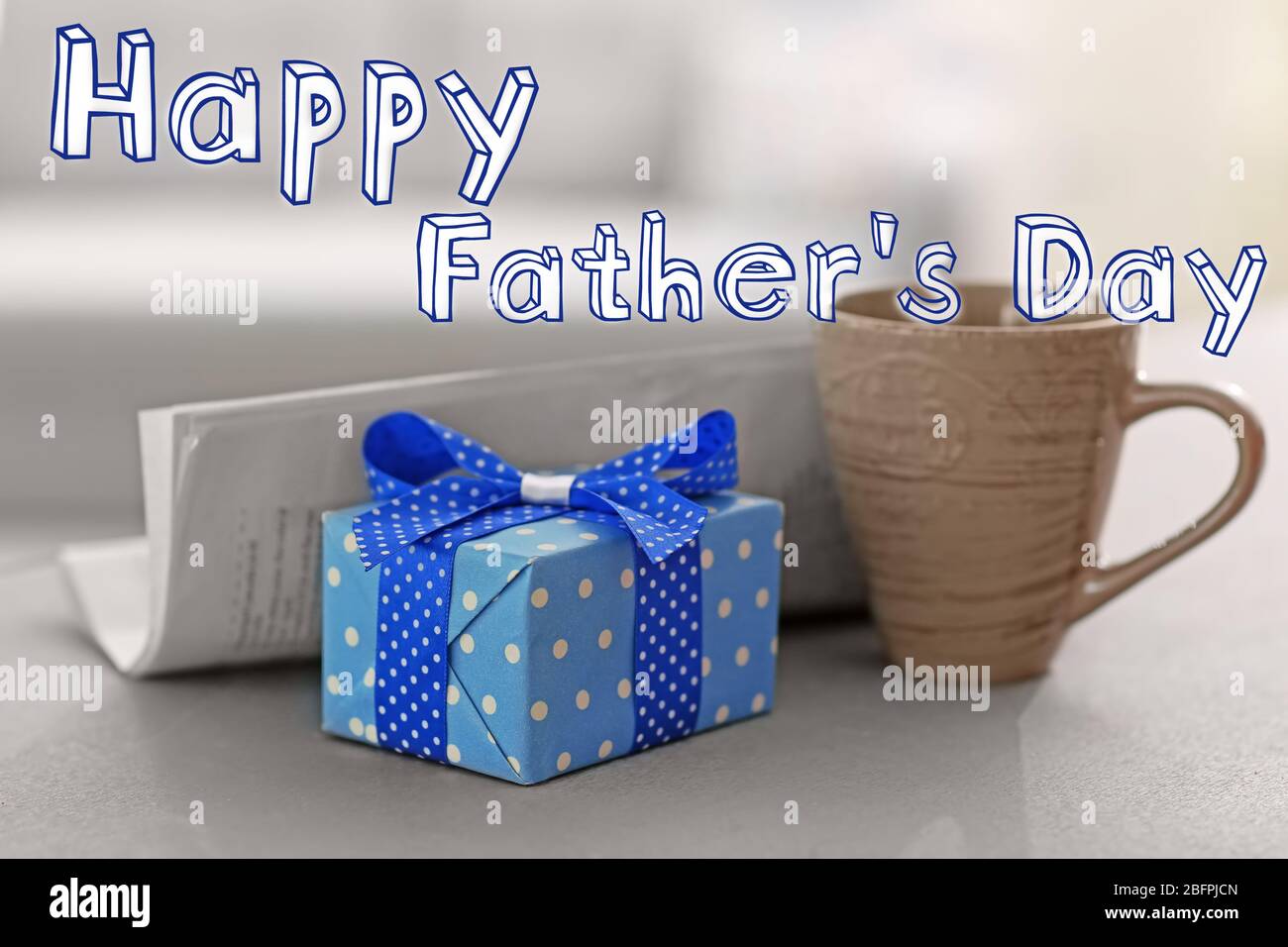 Cup with gift box and newspaper on table. Text HAPPY FATHER'S DAY on background Stock Photo