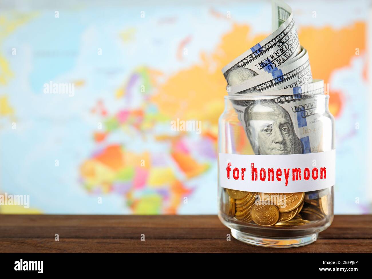 Money savings for honeymoon in glass jar and world map on background Stock Photo