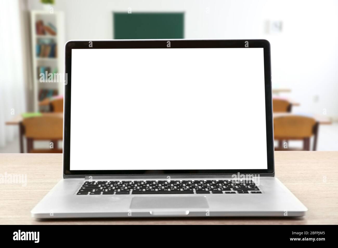 Modern laptop with blank screen on table in classroom Stock Photo