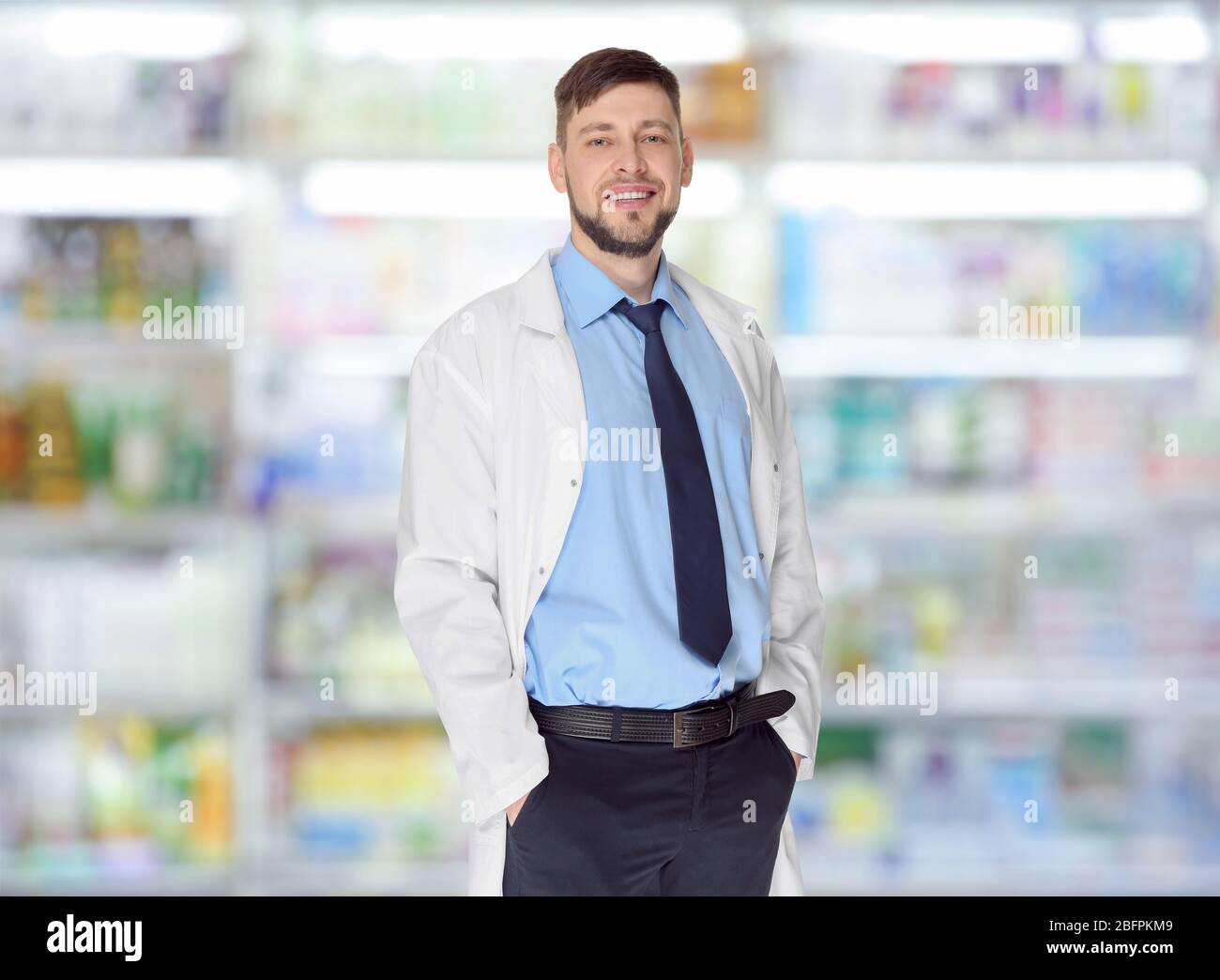 Male pharmacist at work. Blurred shelves with pharmaceutical products on background Stock Photo