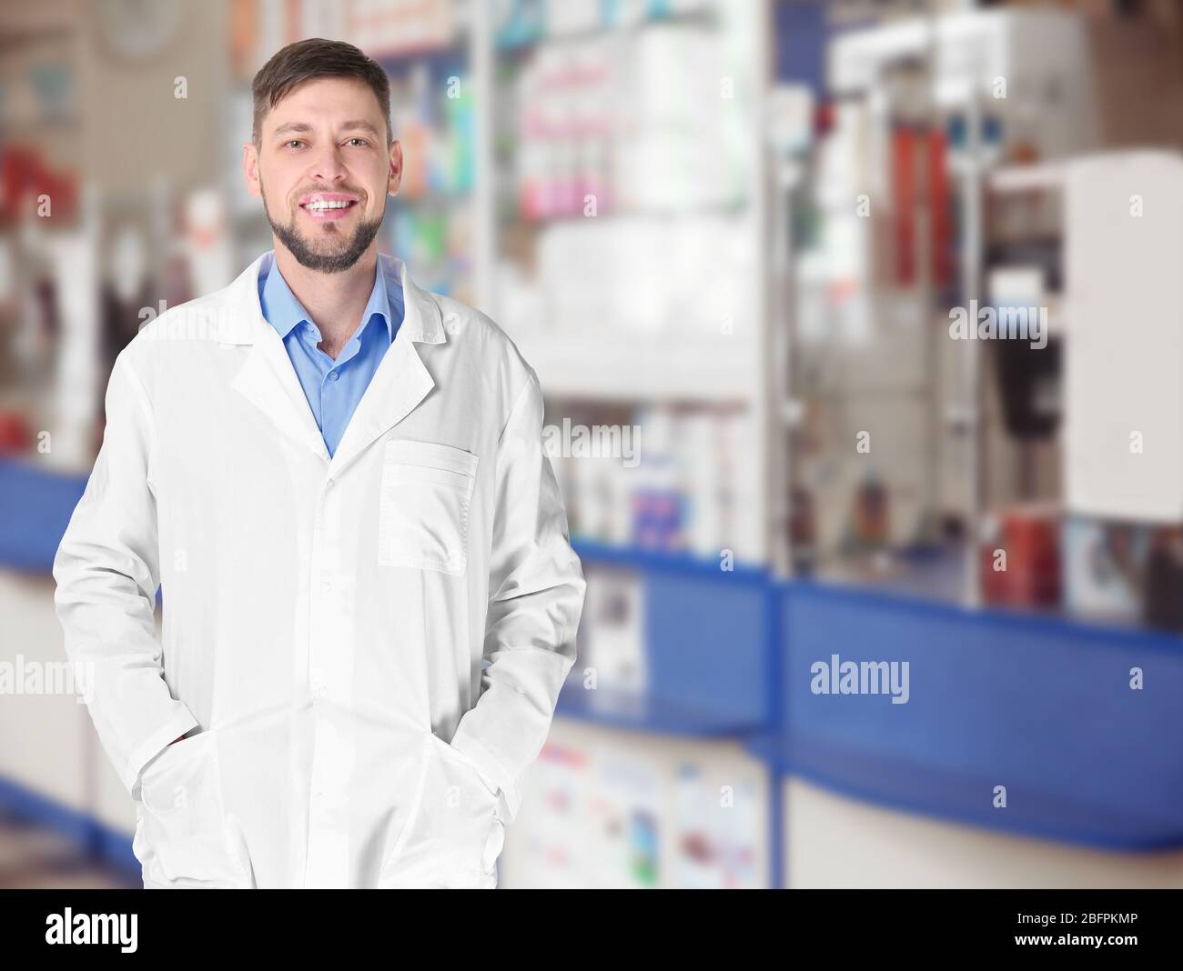 Male pharmacist at work. Blurred shelves with pharmaceutical products on background Stock Photo