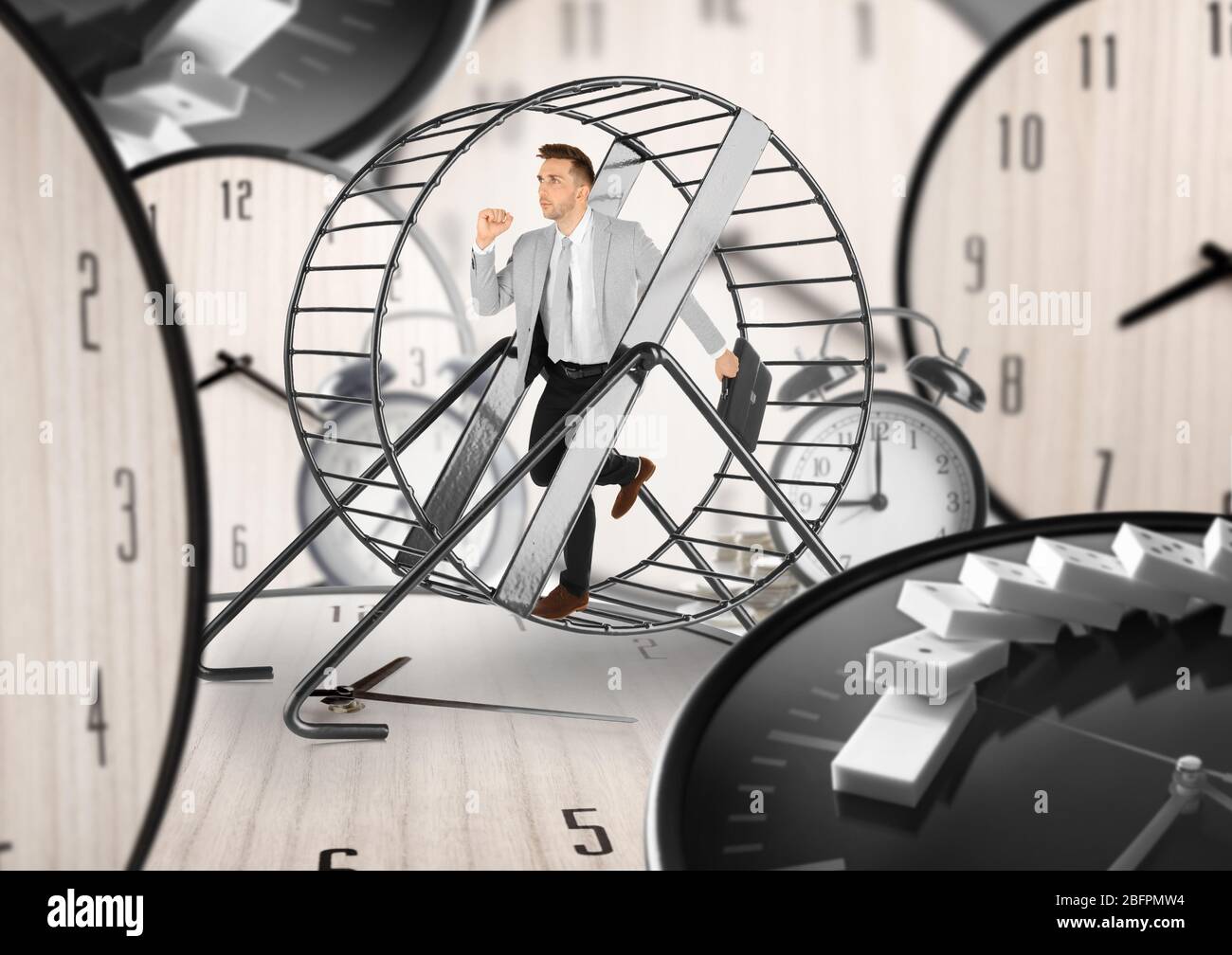 Young man running in wheel and clocks on background. Business rat race concept Stock Photo