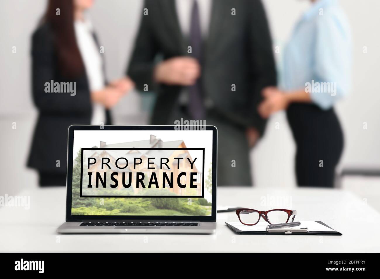 Modern laptop and people on background. Property insurance concept Stock Photo