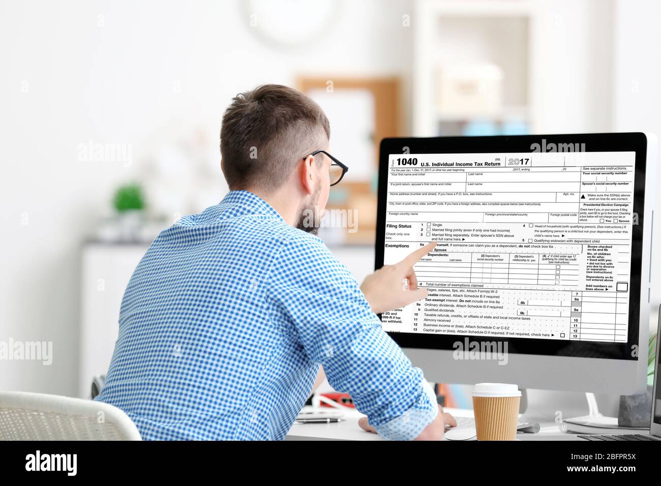 Man using computer for filling in individual income tax return form at ...