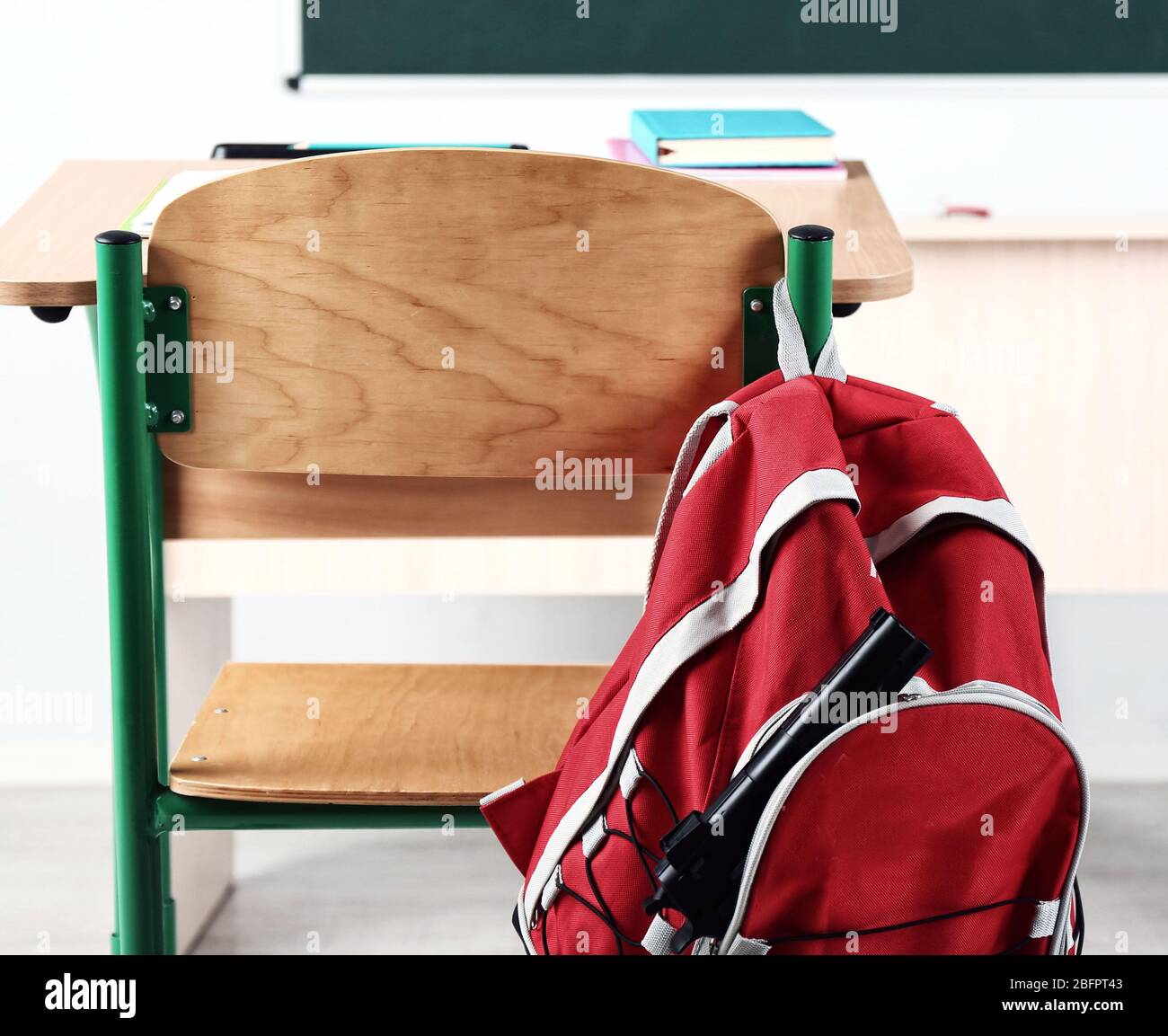 Backpack with gun hanging on chair in classroom. School shooting