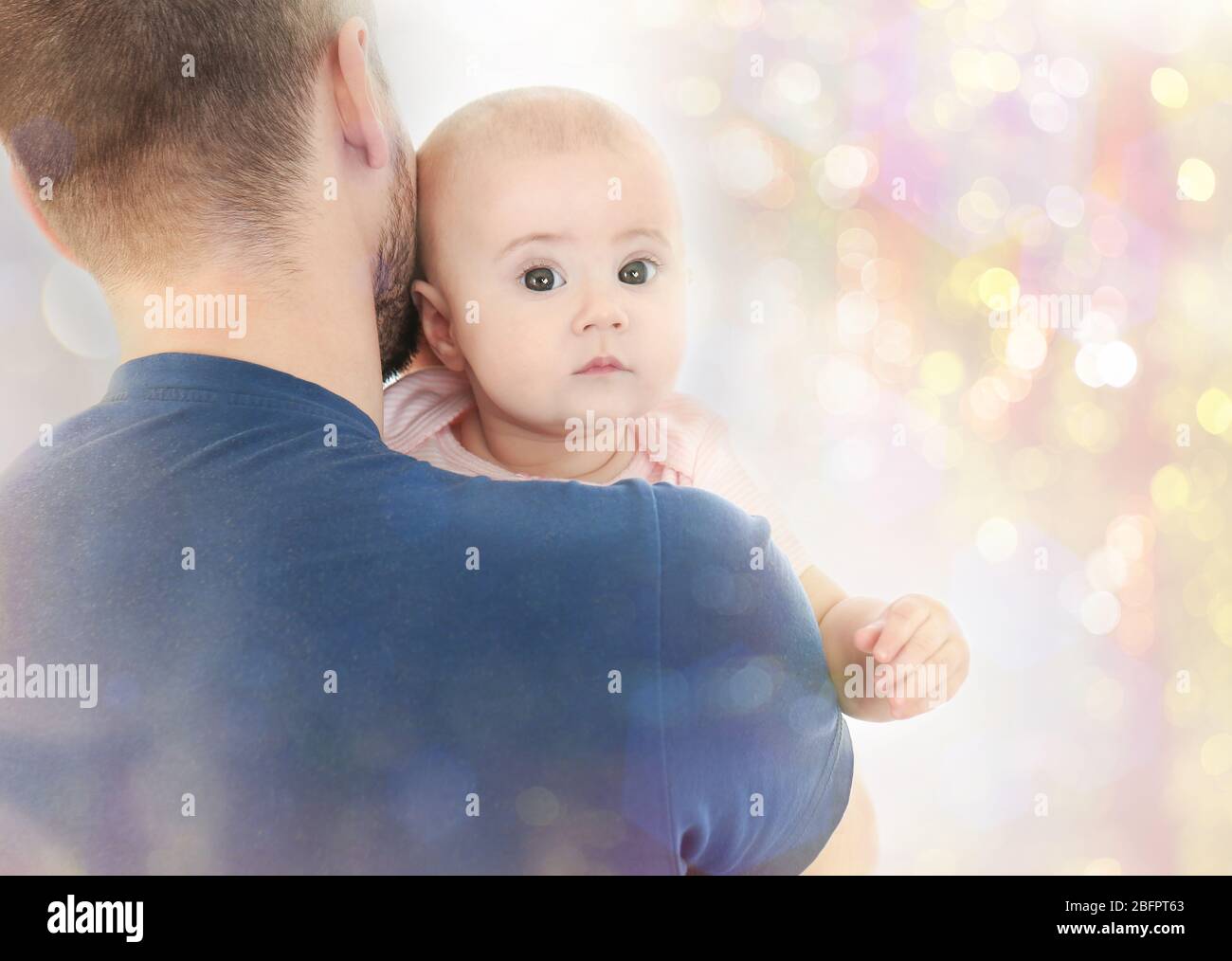Father with baby on Christmas lights background Stock Photo