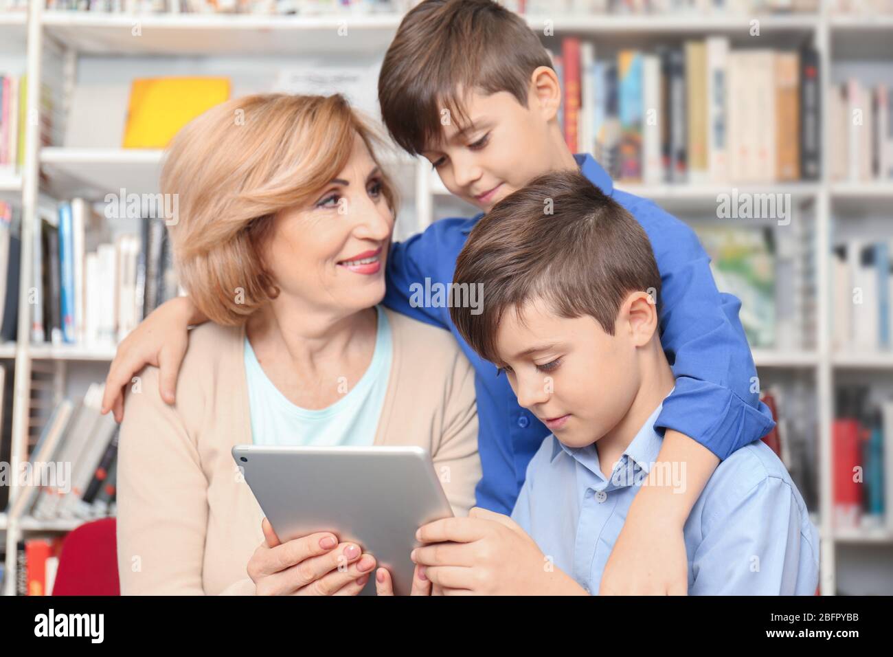 Teacher and children with tablet at school library Stock Photo Alamy