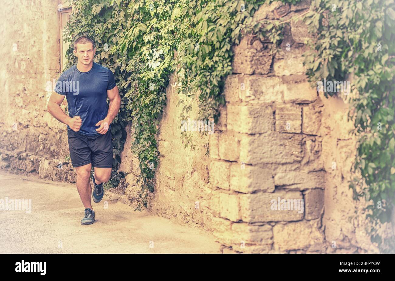 Young sporty man running in park Stock Photo - Alamy