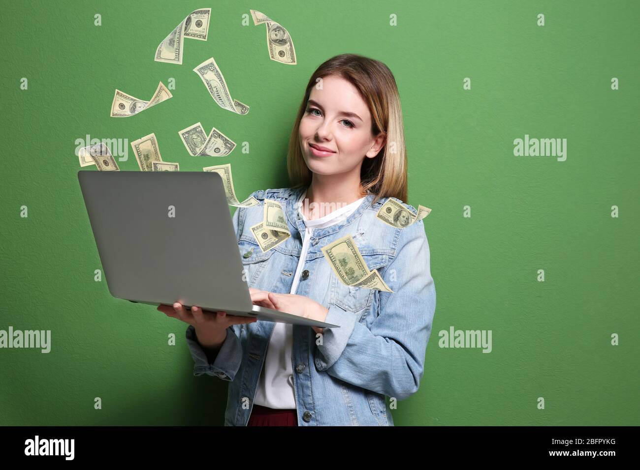 Money flying out of laptop while woman using it on green background ...
