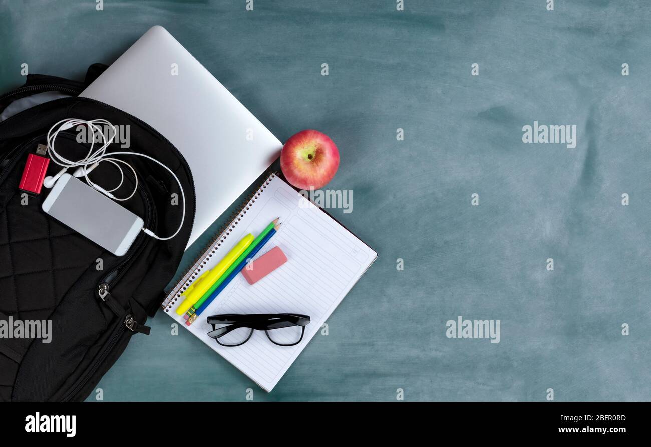 Back to school concept with basic modern technology and traditional educational objects on erased green chalkboard background Stock Photo
