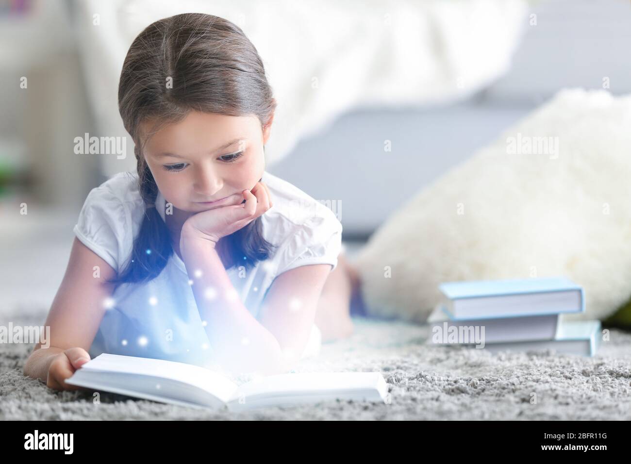 Cute little girl reading book at home Stock Photo - Alamy