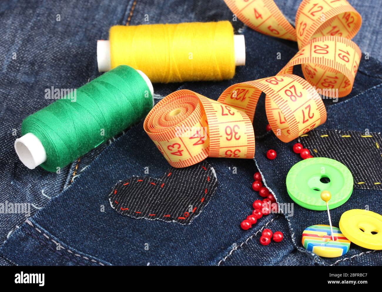 Heart-shaped patch on jeans with threads and buttons closeup Stock Photo
