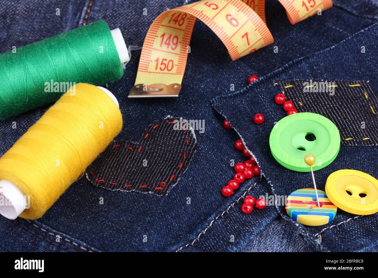 Heart-shaped patch on jeans with threads and buttons closeup Stock Photo