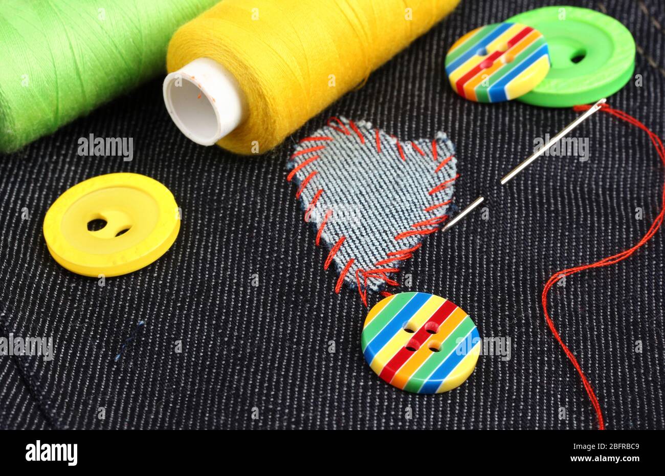 Heart-shaped patch on jeans with threads and buttons closeup Stock Photo