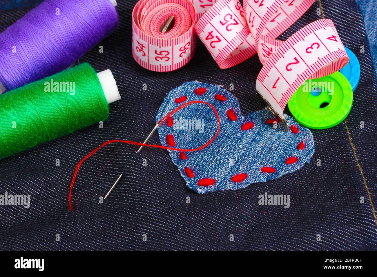 Heart-shaped patch on jeans with threads and buttons closeup Stock Photo