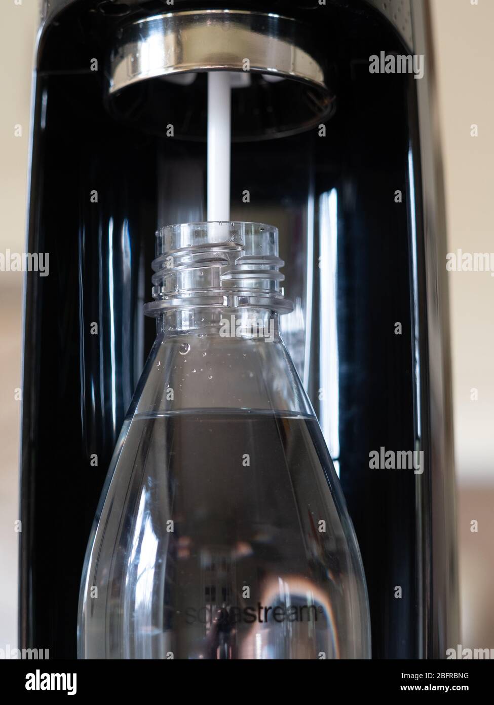 Close Up of black Sodastream carbonator and reusable Sodastream plastic bottle with water, photographed at eye level. Stock Photo