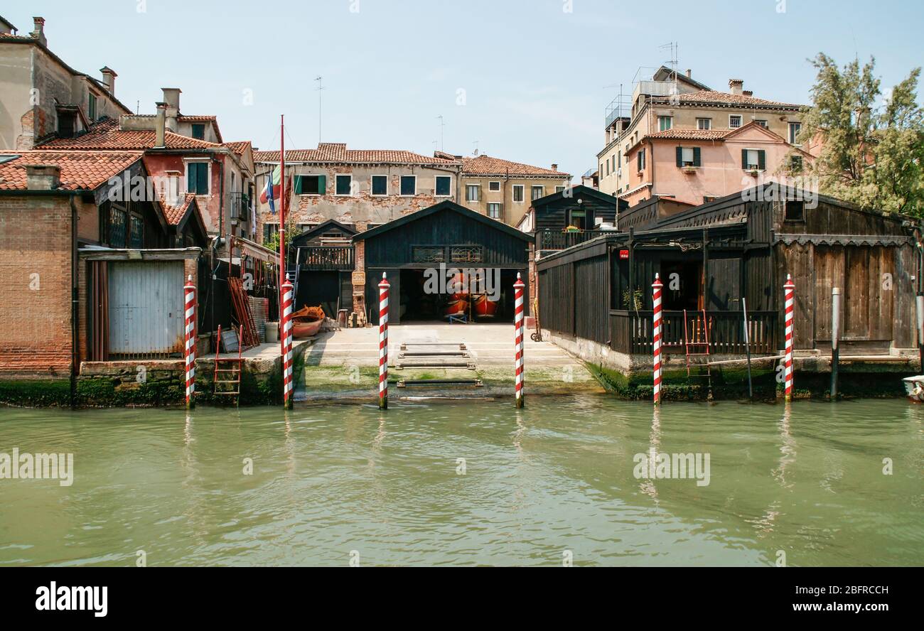 Red and white striped mooring poles mark the canal entrance to a boat storage business. Venice, Italy. no people Stock Photo