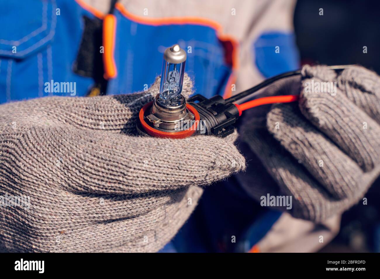Car service men. Replacing a burnt out lamp in the car headlight Stock