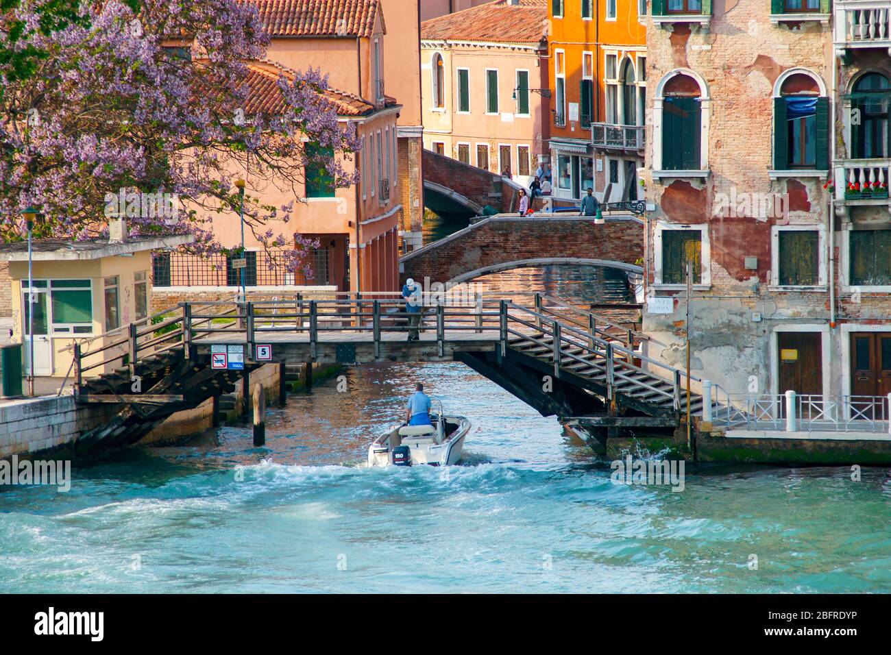 Late afternoon sun and shadows on a motorboat heading into a small canal from the Grand Canal. Stock Photo