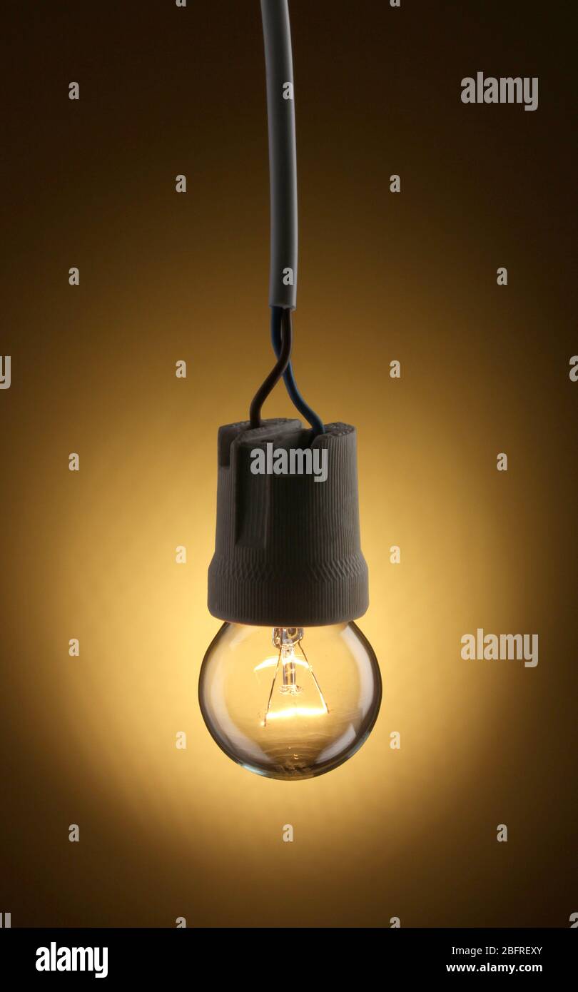 A lit light bulb on yellow background Stock Photo - Alamy