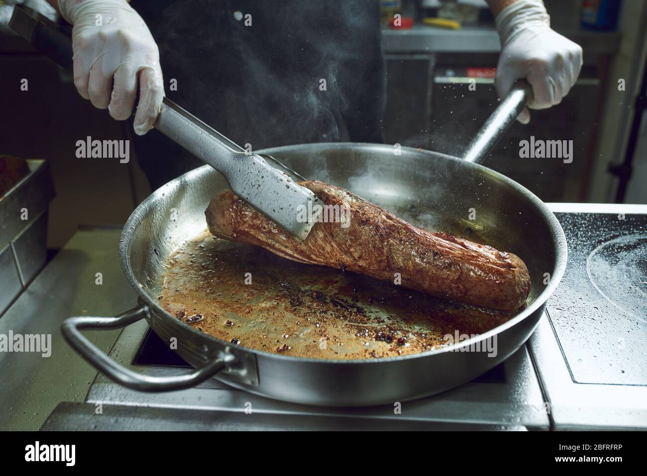 The chef works in the kitchen of the restaurant. Fresh meat roasted in ...