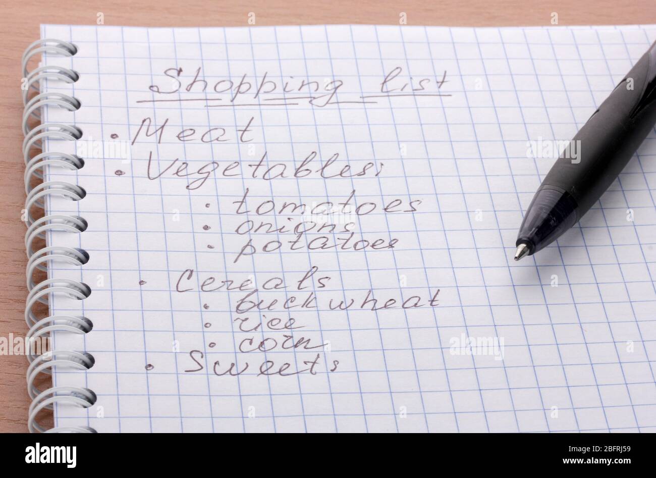 Shoping list and pen on wooden table Stock Photo