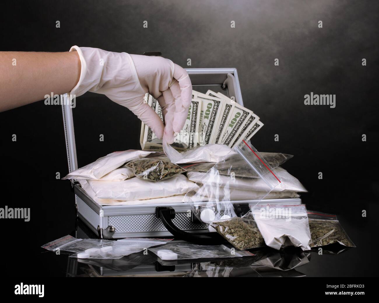 Cocaine and marijuana in a suitcase wiht hand holding a package of cocaine isolated on white Stock Photo