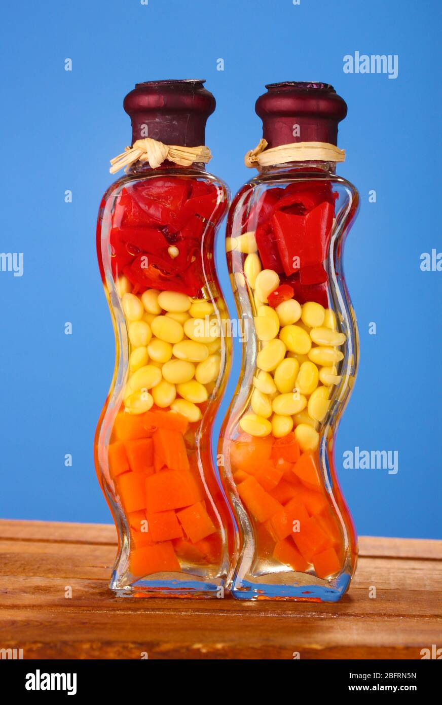 Two Bottles With Red Pepper Beans Carrots For Kitchen Decor On Blue Background Stock Photo Alamy