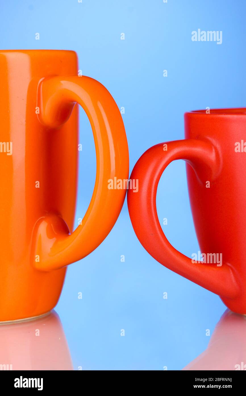 Two colored cups handles close-up on blue background Stock Photo
