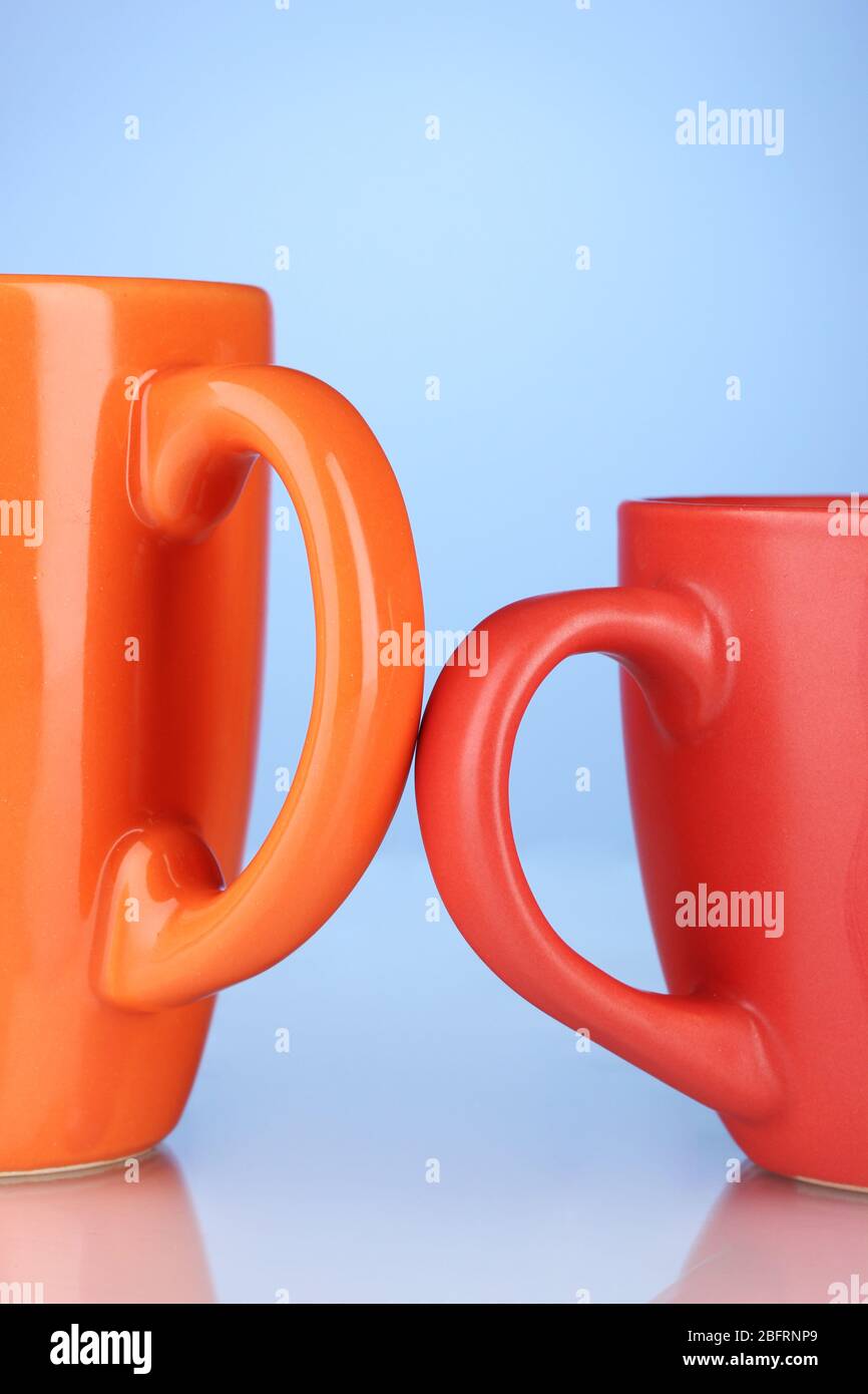 Two colored cups handles close-up on blue background Stock Photo