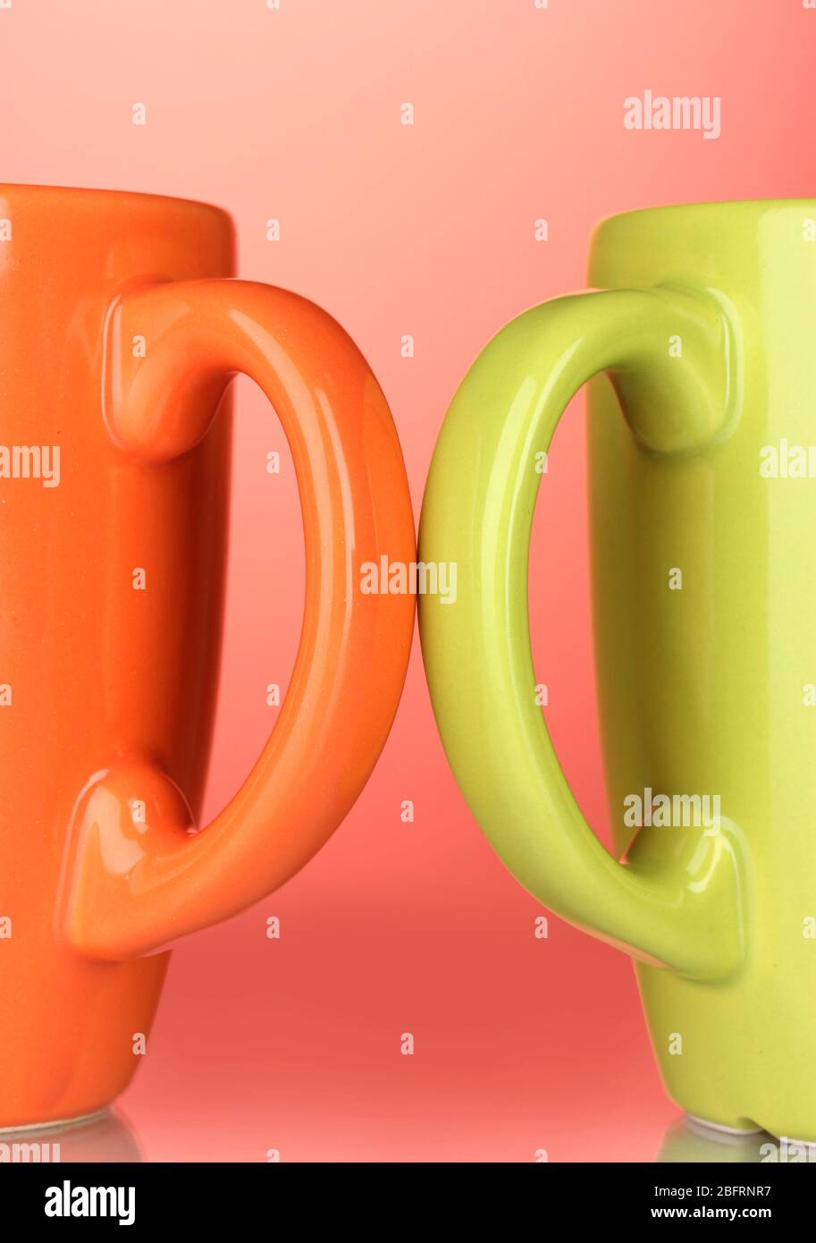 Two colored cups handles close-up on red background Stock Photo