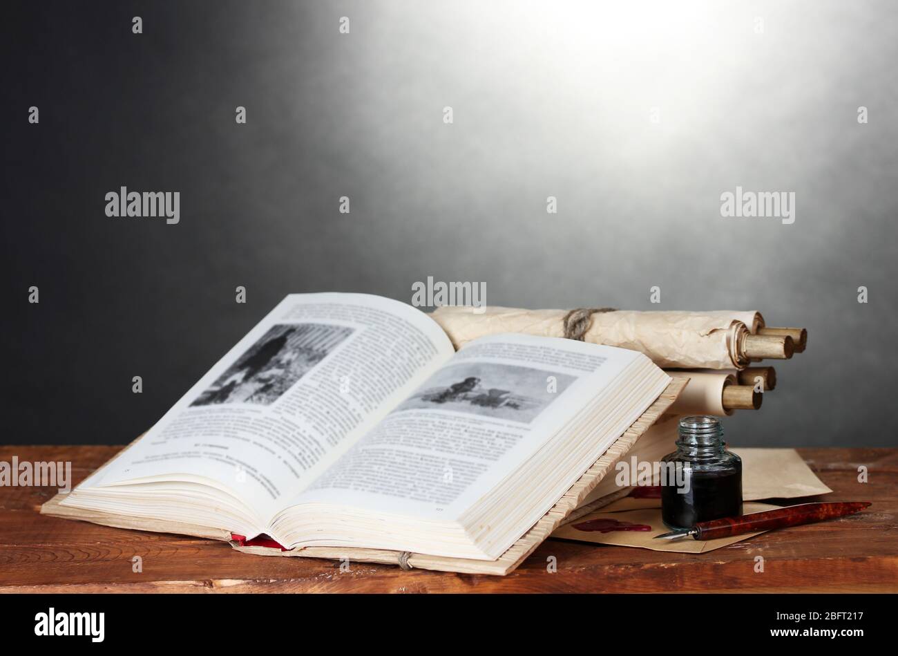 old books, scrolls, ink pen and inkwell on wooden table on grey ...